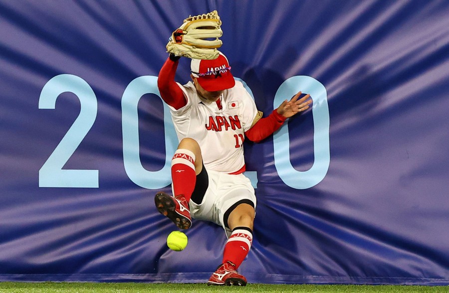 A softball player stumbles into a padded wall.