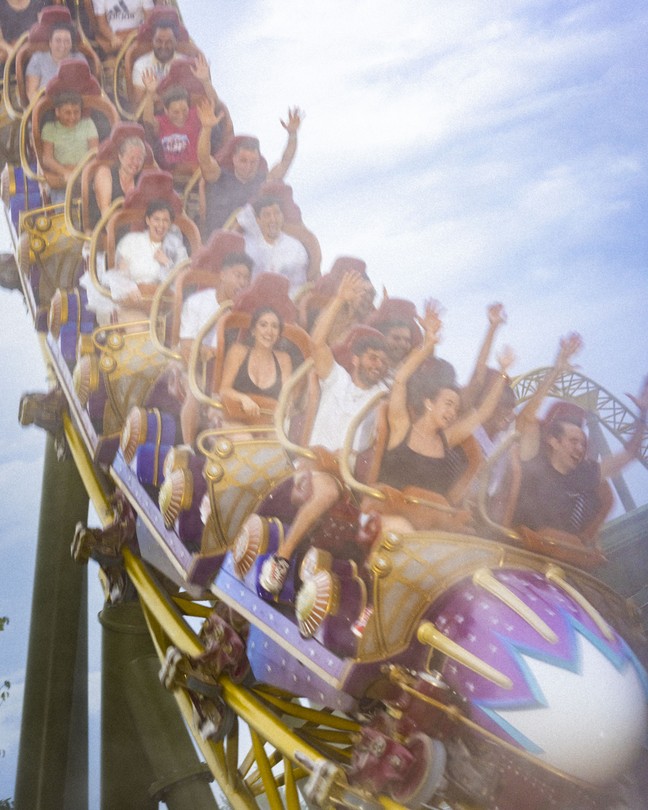 a color photograph of people riding a roller coaster