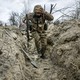 A photo of a Ukrainian soldier running through a trench