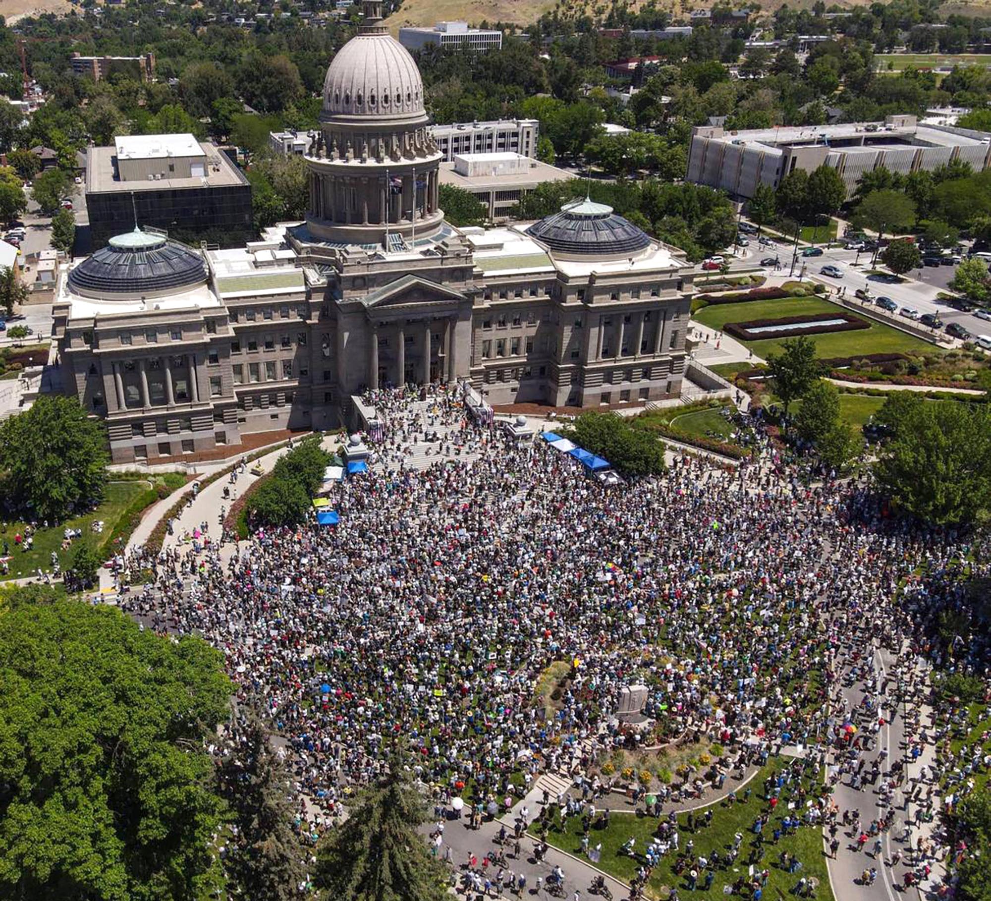 An aerial view of a large crowd of protesters standing outside a state capitol building.