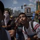 Protesters look at a flag of Maduro burning near Las Mercedes in Caracas.