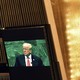 Image of Trump speaking set against a bright gold wall with a UN logo background