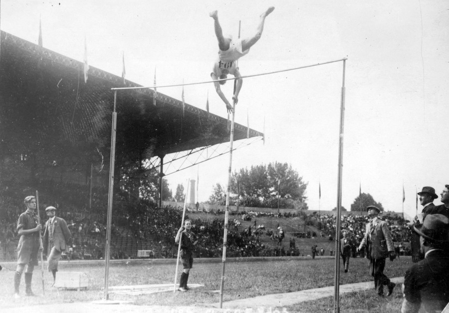 An athlete seen at the top of a pole-vault attempt