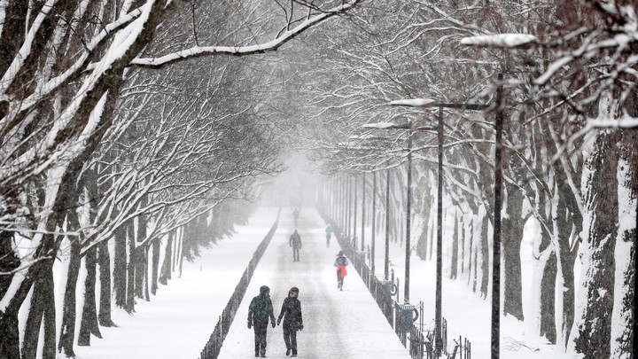 People walk down a path on the National Mall during a snowstorm.