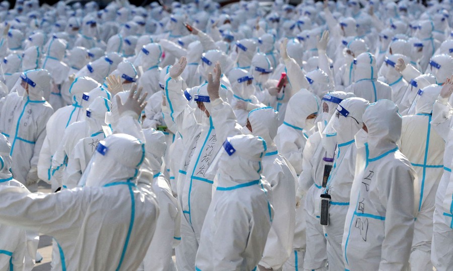 Hundreds of medical workers in protective suits wave to residents.