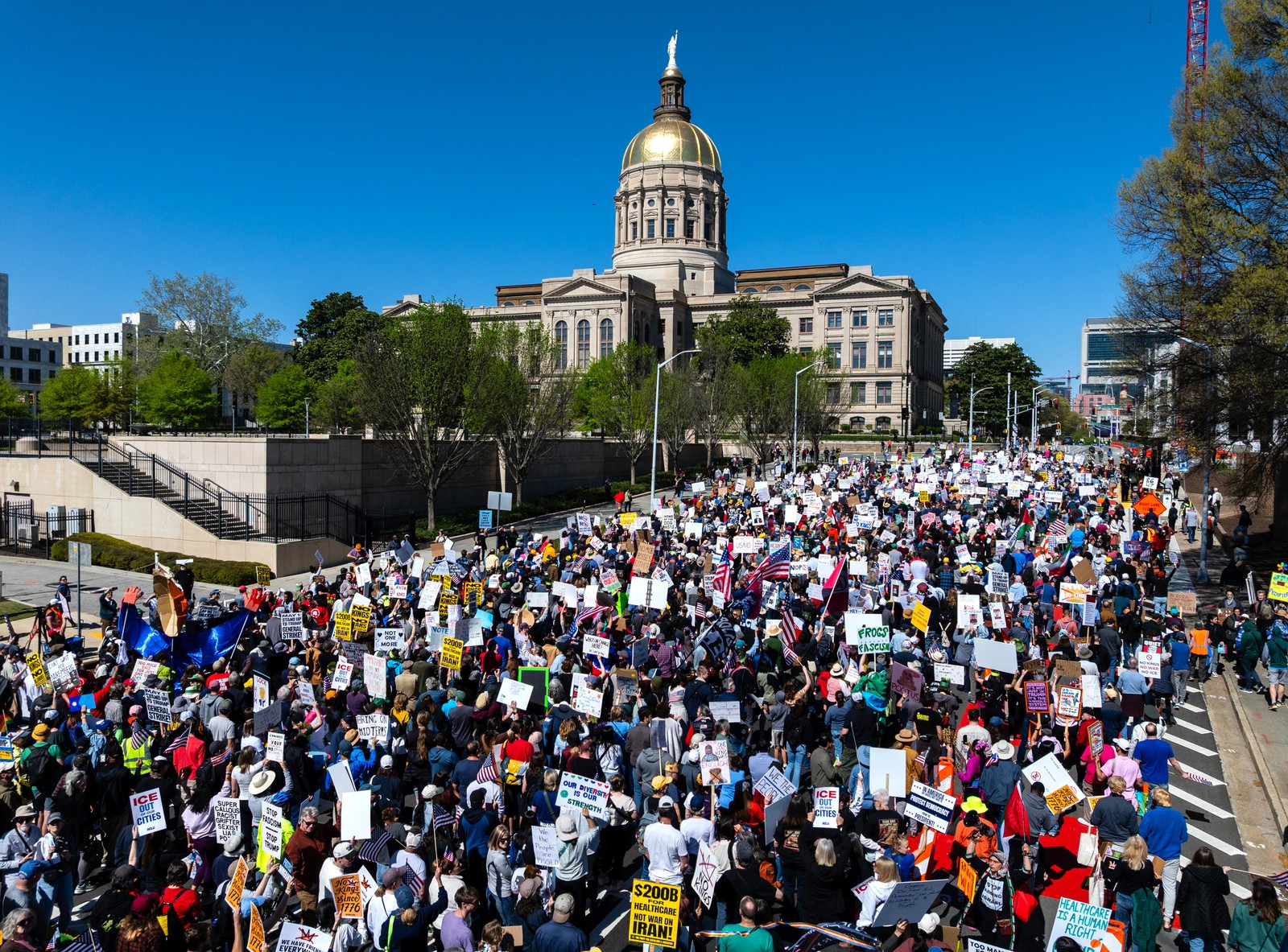 A large crowd of protesters walks outside a state capitol building.