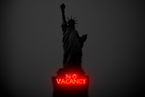 The Statue of Liberty, with a "No Vacancy" neon sign on the pedestal