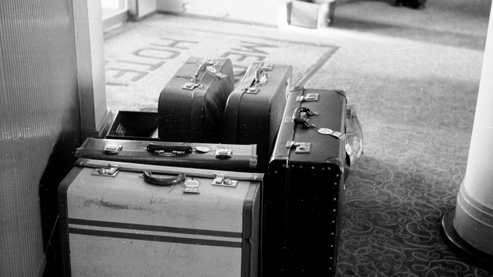 A black and white photograph of suitcases sitting by an entryway