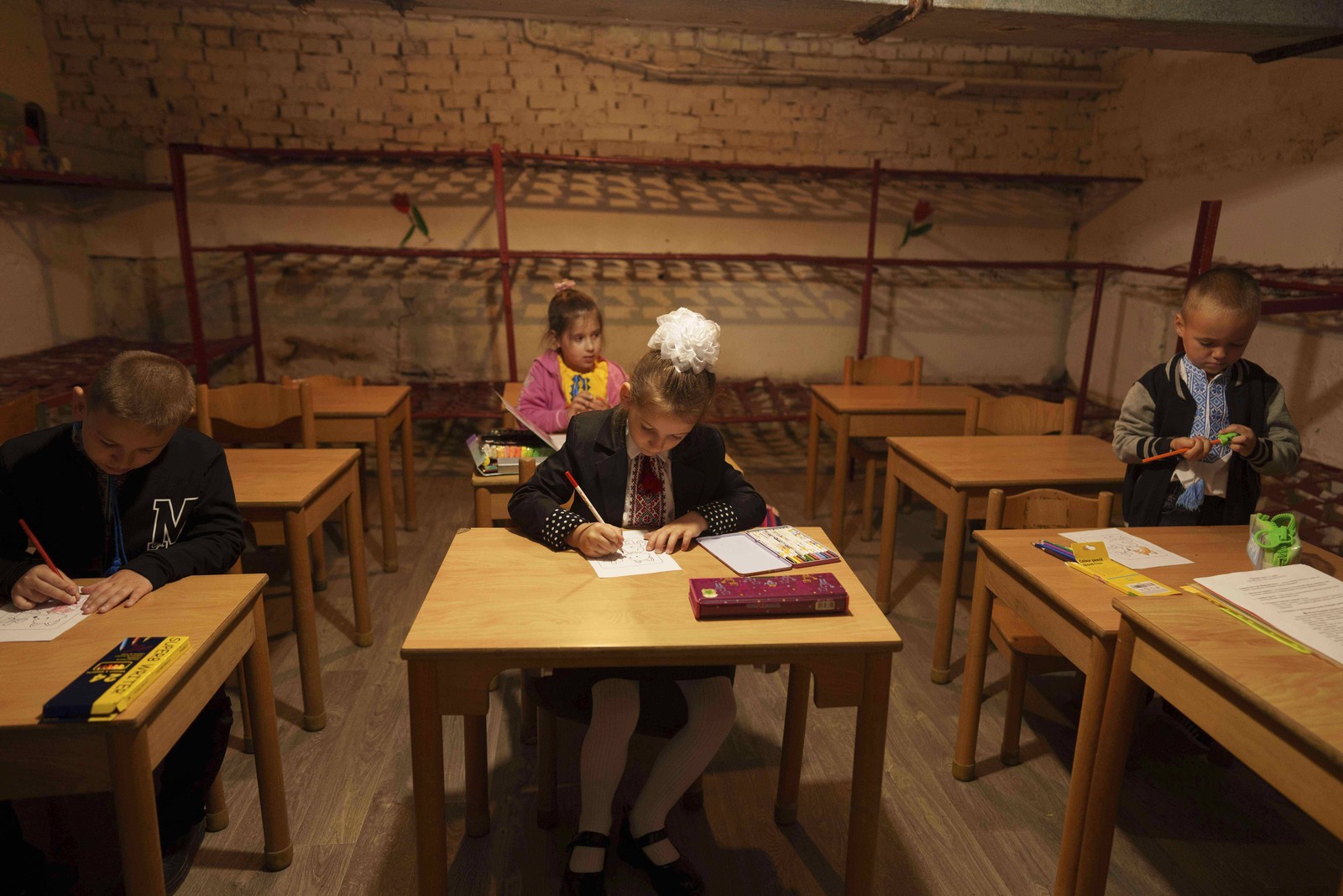 Several students sit at desks during a class in a windowless school room.