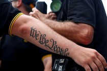 A person's arm has a tattoo that says "We The People"