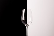 A photo of an empty wine glass in front of a black and white backdrop