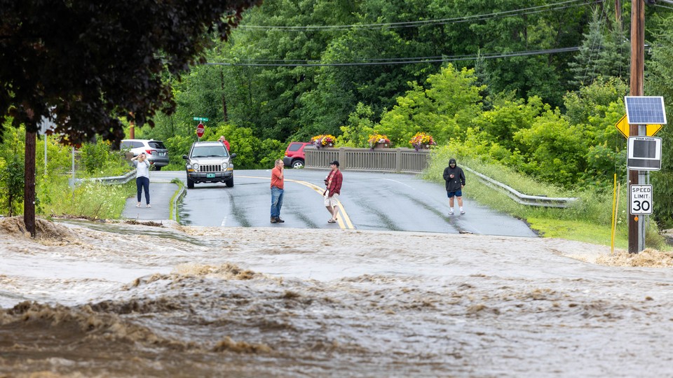 Onlookers inspect a flooded road in Southern Vermont
