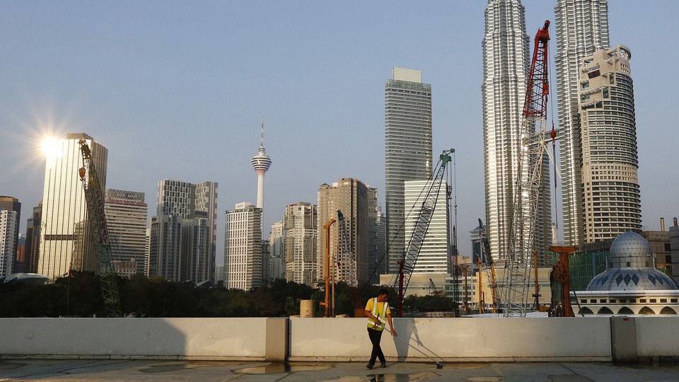 A worker sweeping the ground in front of skyscrapers