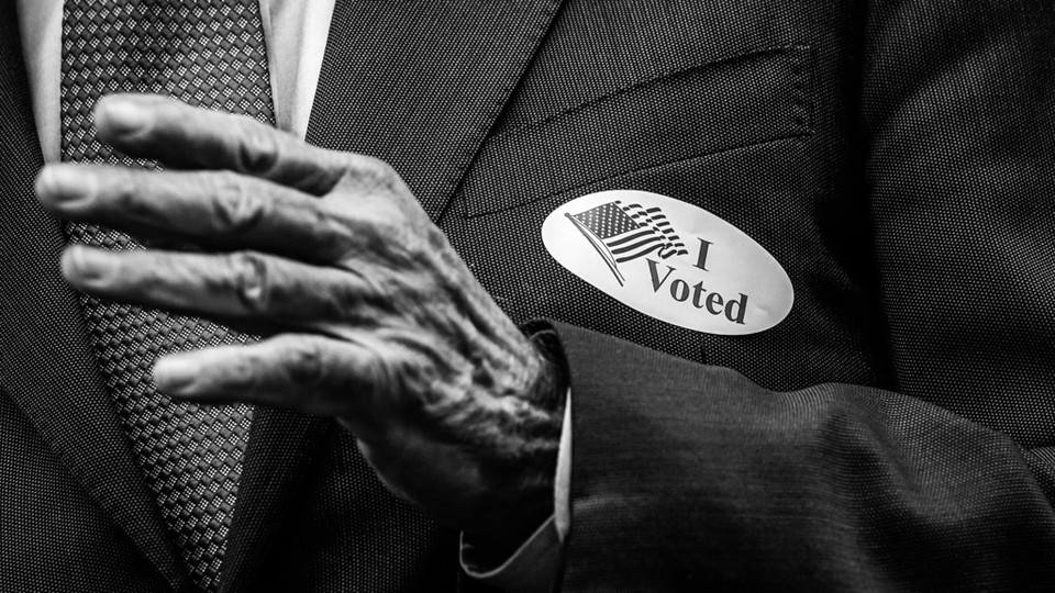 An elderly person wearing an “I voted” sticker