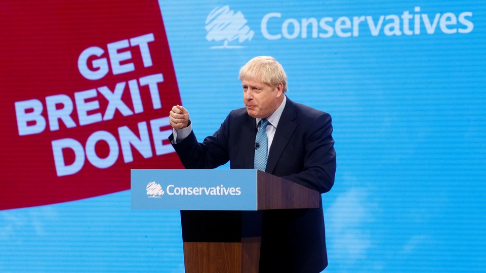 Boris Johnson speaks in front of a lectern with a banner for his Conservative Party behind him.