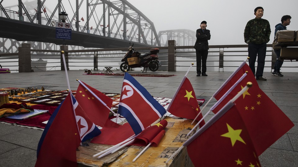 Chinese vendors sell North Korea and China flags on the boardwalk next to a bridge that connects China and North Korea.