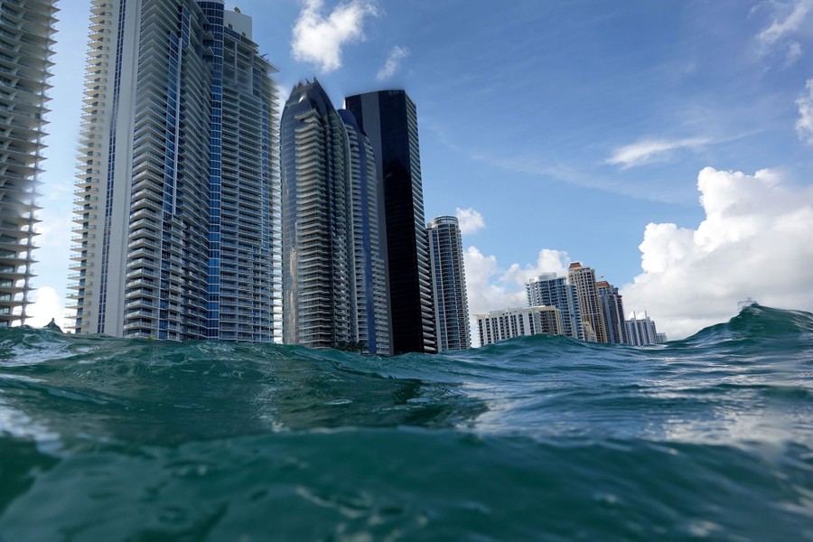 Tall condo buildings stand along a beach, seen from the water.