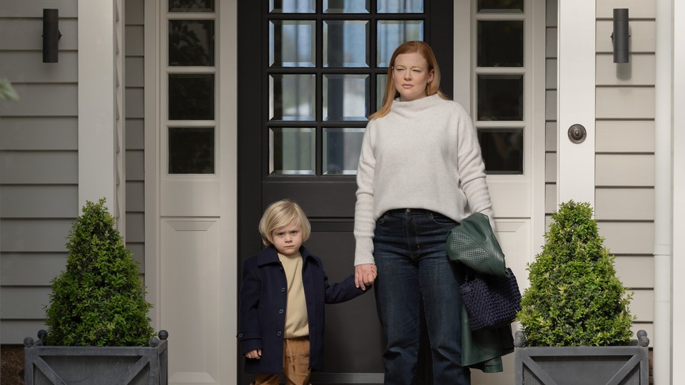 A still photo of Sarah Snook as Marissa, holding her son's hand in front of the door of a house, on "All Her Fault."