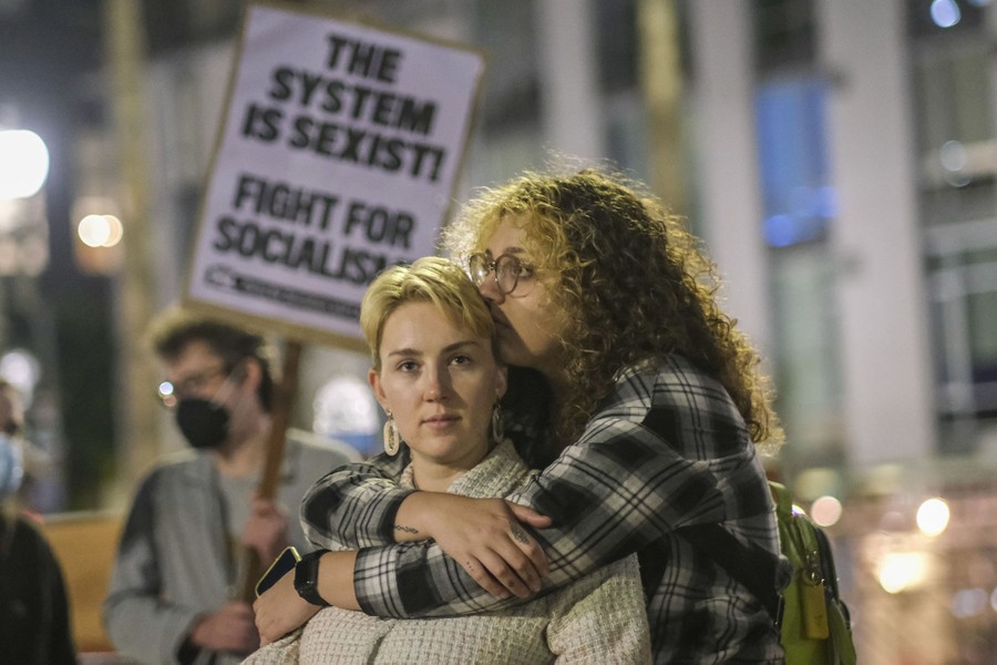Two women embrace in a city square, after a protest.