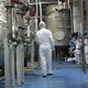 A technician in scrubs walking among machinery