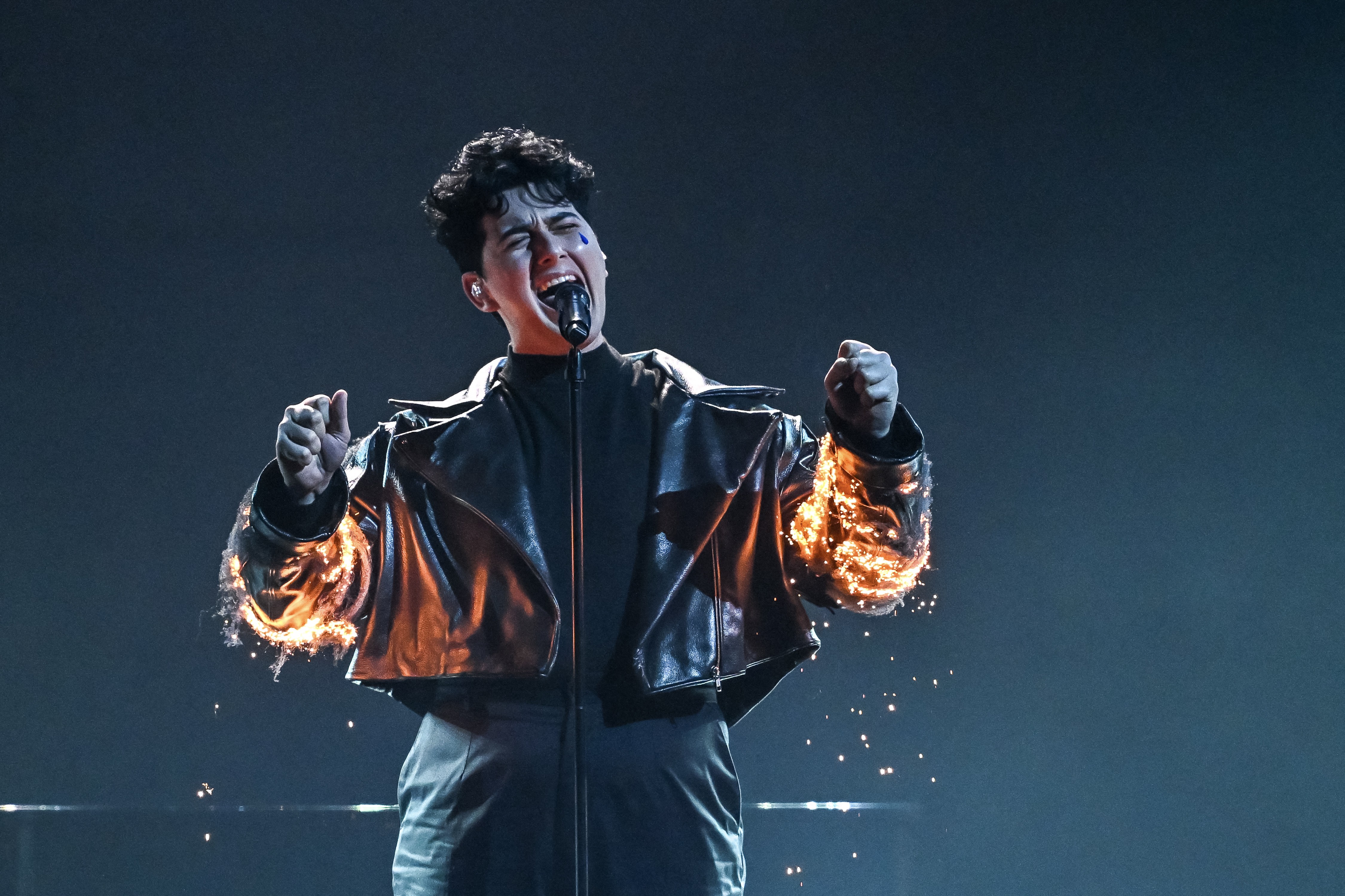 Performers sing, and sparks seem to burst out from the sleeves of their costumes.