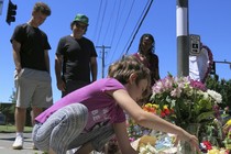 Angel Sauls, left, helps her stepdaughter, Coco Douglas arrange a sign and some painted rocks she made for a memorial in Portland, Oregon.