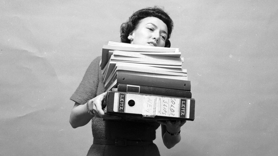 A black-and-white photo of tired woman holding a bunch of files