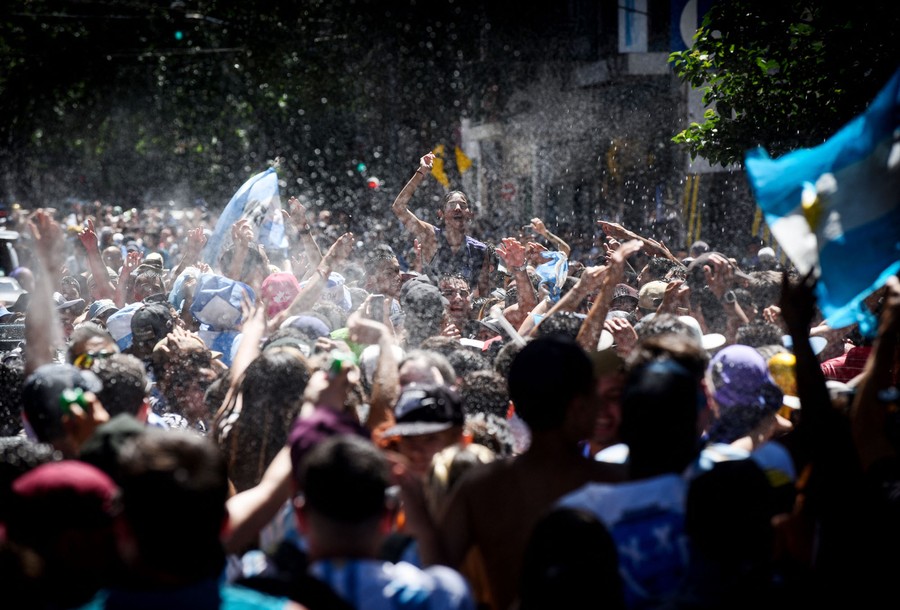 A crowd of people celebrate and throw water in the air.