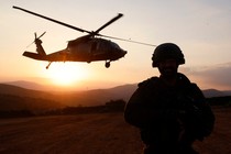 An Israeli soldier looks on as a military helicopter hovers.