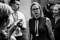 Senator Kyrsten Sinema walks down a hallway