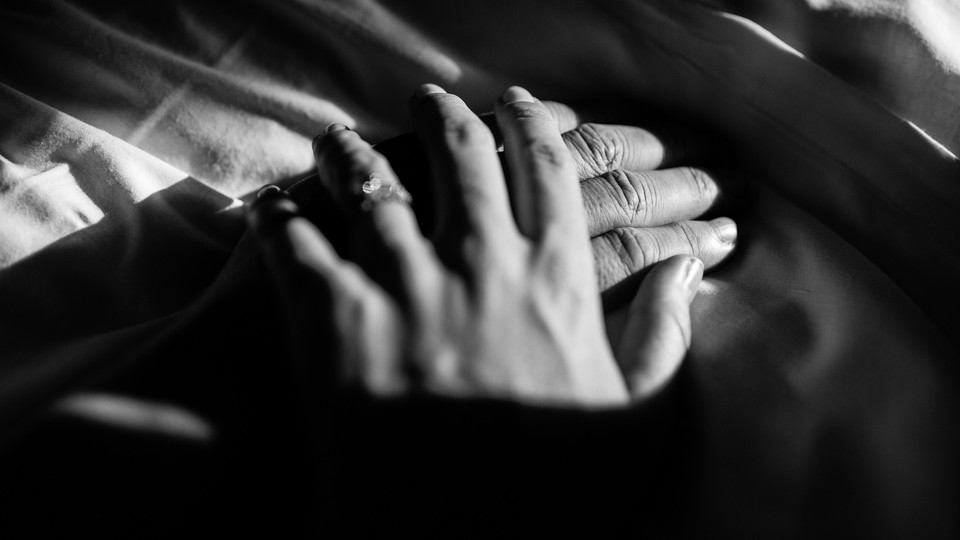A black-and-white photo of a woman's hand resting over a man's hand