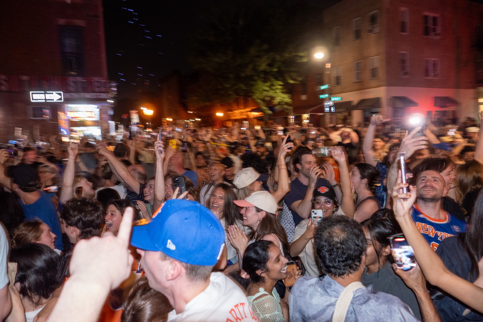 A large crowd of people celebrating in an intersection in a city.