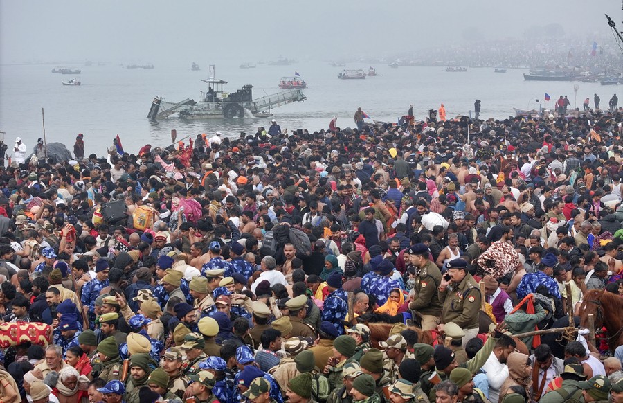 A large crowd of worshippers gather on a riverbank.