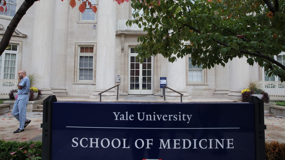 A man in scrubs walks outside the Yale School of Medicine.
