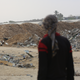 A Palestinian man in the foreground faces the direction of a concrete block marking the "yellow line" in the background.