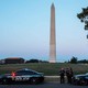 Photograph of two United States Park Police Cars with sirens on in front of the Washington Monument in DC.