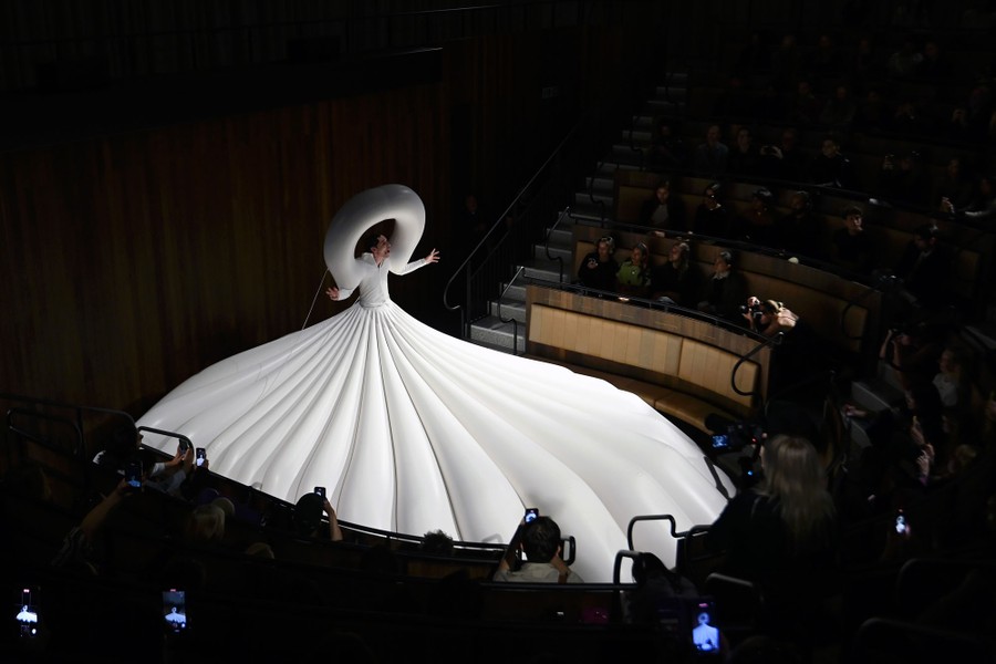 A singer performs while wearing a huge garment that is partially inflated to occupy most of a stage.