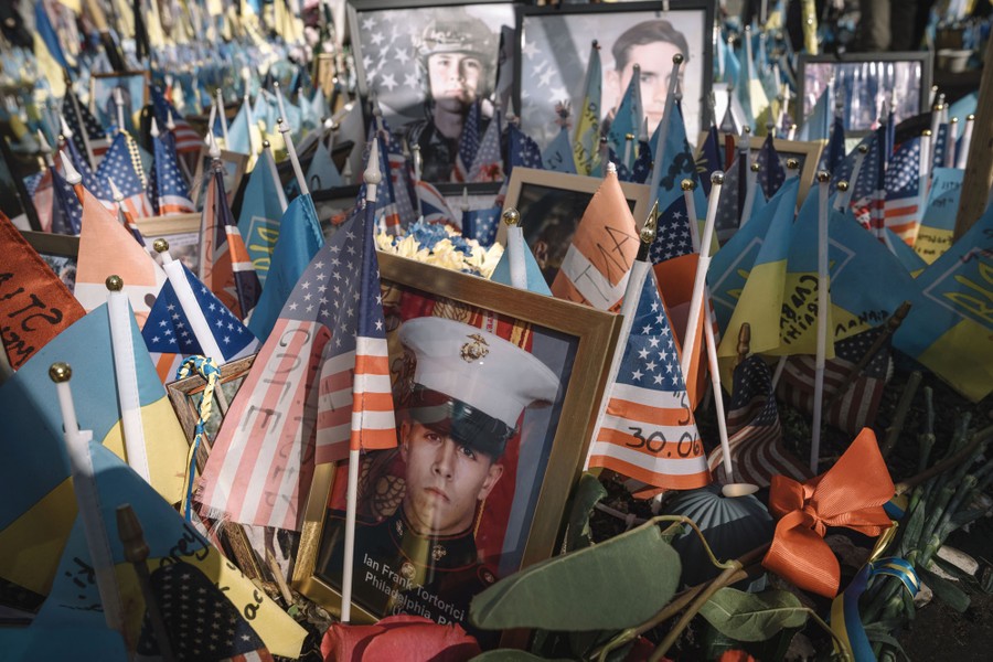 Framed photo portraits of soldiers sit among American and Ukrainian flags in a makeshift memorial.