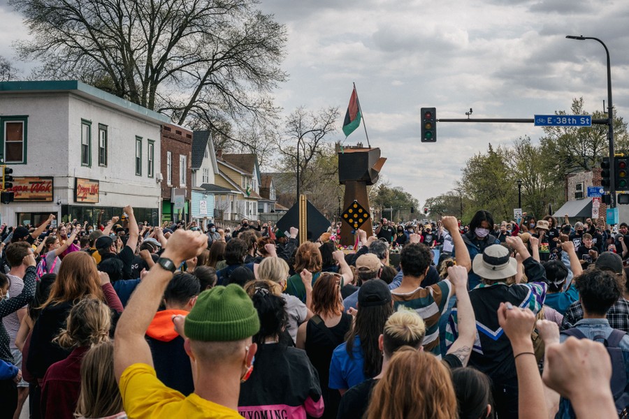 Hundreds of protesters can be seen gathered in an intersection, most raising one fist in the air.