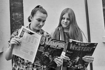 Two teenage girls reading comic books