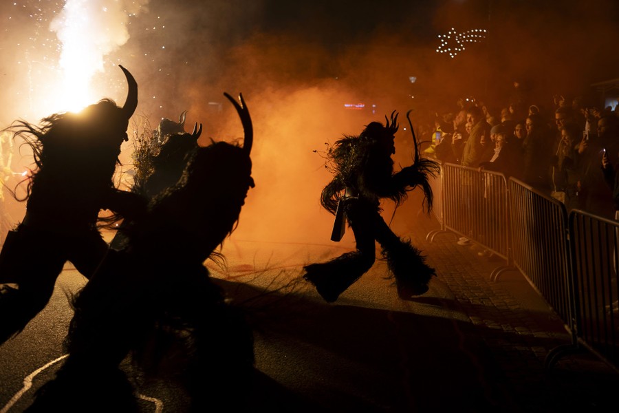 Several people wearing frightening furry Krampus costumes run during a performance.