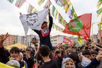 A man holds up a flag of a jailed Kurdish leader at a festival