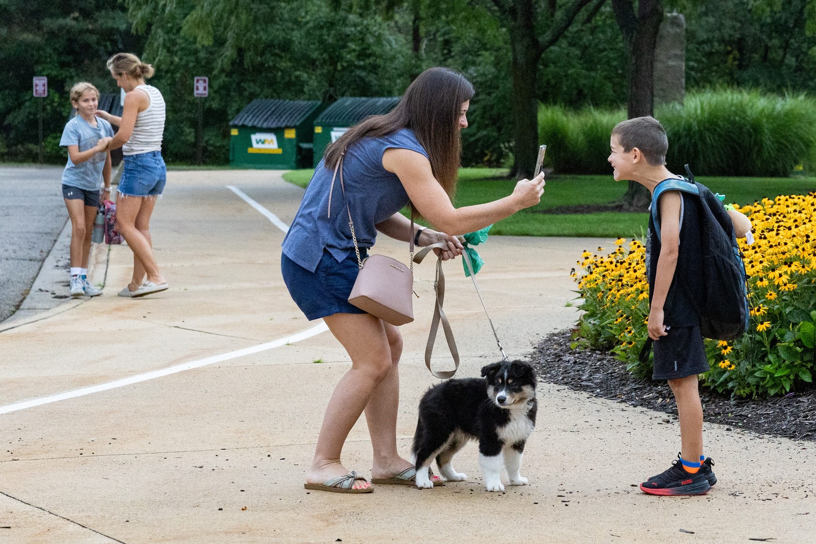 A boy stands and makes a silly pose for his mother who takes a picture.