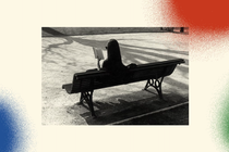 A black-and-white photo features a woman sitting on a park bench with her back to the camera. She is reading a book, and on the ground, the shadow of a tree is stretching toward her. The photo is set against a background with three spray-painted circles. In the bottom-left corner is a blue one, in the bottom-right corner is a green one, and in the top-right corner is a red one.