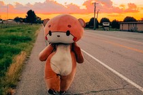 A man in a bear suit walking along a road