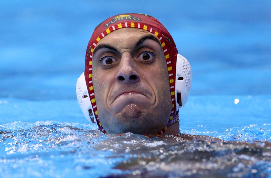 A water polo player makes an intense face while swimming during a game.