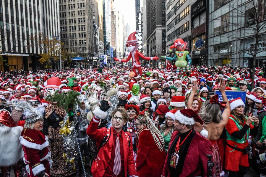 A street in New York City is filled with people dressed as Santa Claus and other holiday characters.