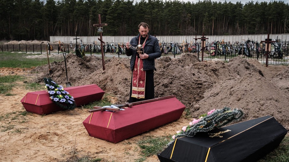 A Ukrainian priest buries the victims of the Bucha massacre. 