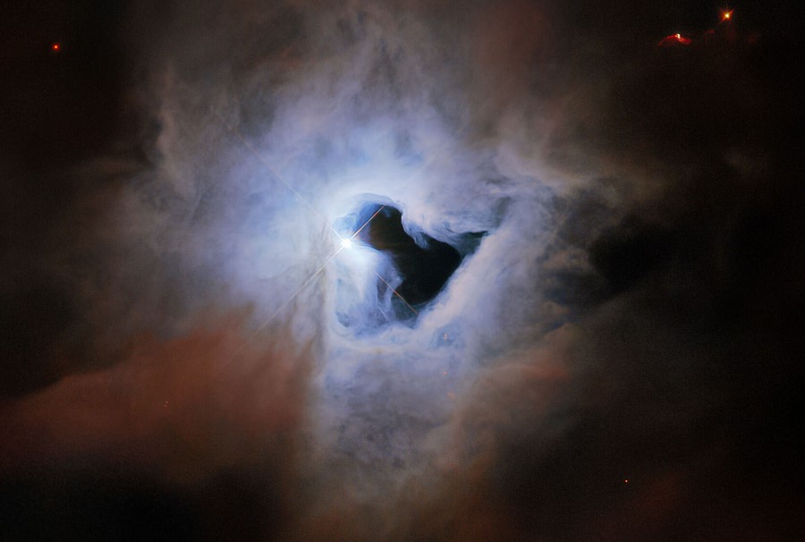 A bright cloud of gas and dust in space, centered around what appears to be a keyhole-shaped dark patch.