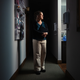 A photo of woman standing in shadowy hallway next to a patient exam room